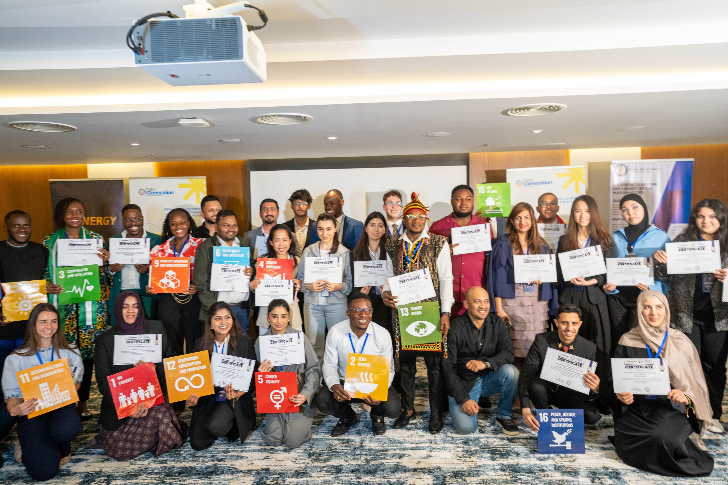 A large group of summit delegates in a conference room holding their certificates and Sustainable Development Goal cards
